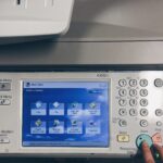 Worker pressing start on a printer