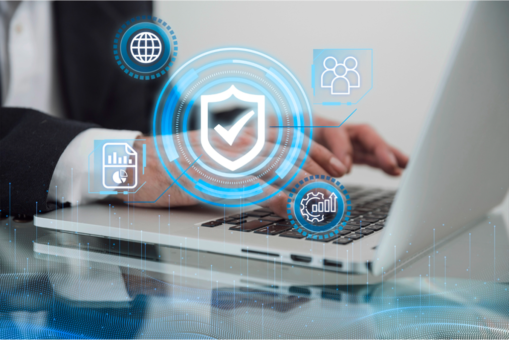 A close-up of hands typing on a laptop with cybersecurity icons floating around.