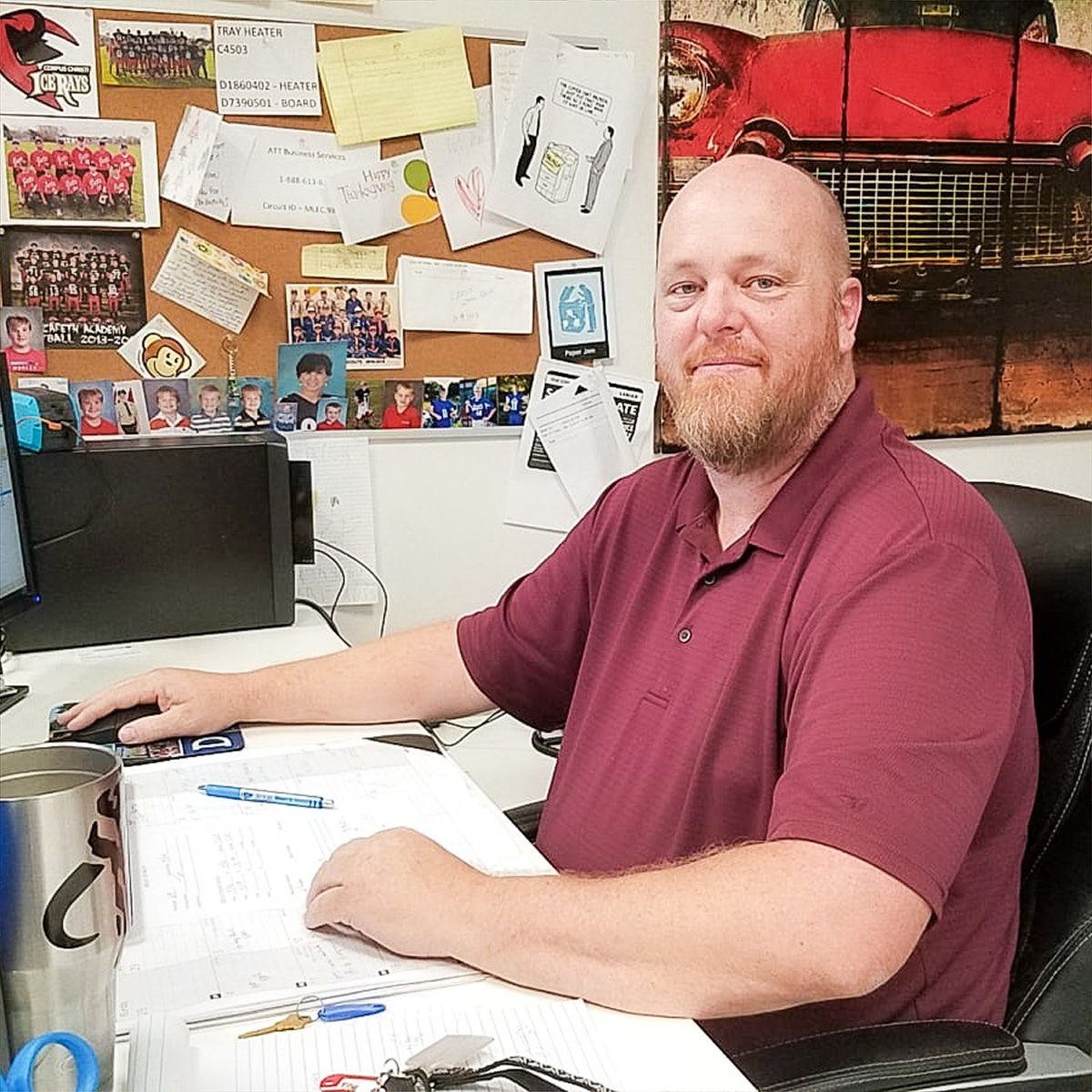 A man smiles as he sits at his desk in a modern office